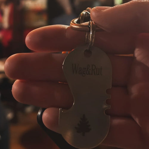 Keychain with 'Wag&Rut' tag held in a hand against a blurred background